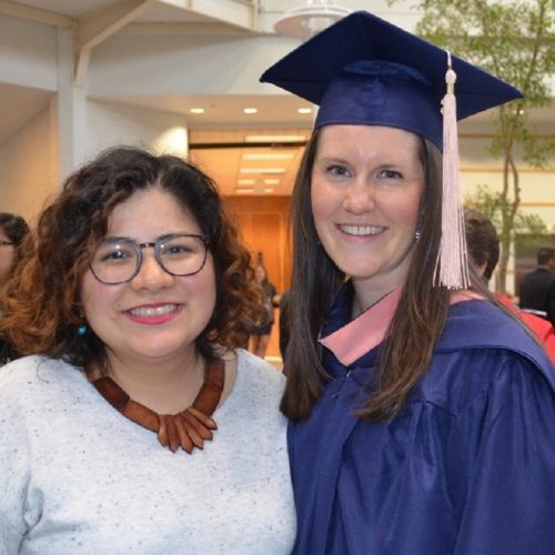 A graduate poses with a Center staff member for a photo at Commencement.