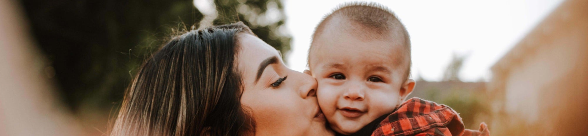 A Latina mother kisses her infant son.