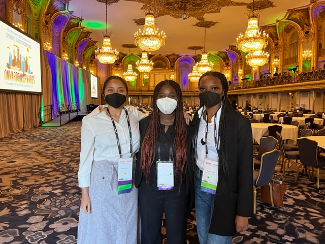 Photo of three woman wearing masks standing in an empty ballroom
