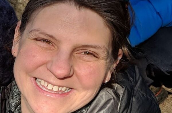 White woman in puffy coat with pulled back brown hair smiling at camera